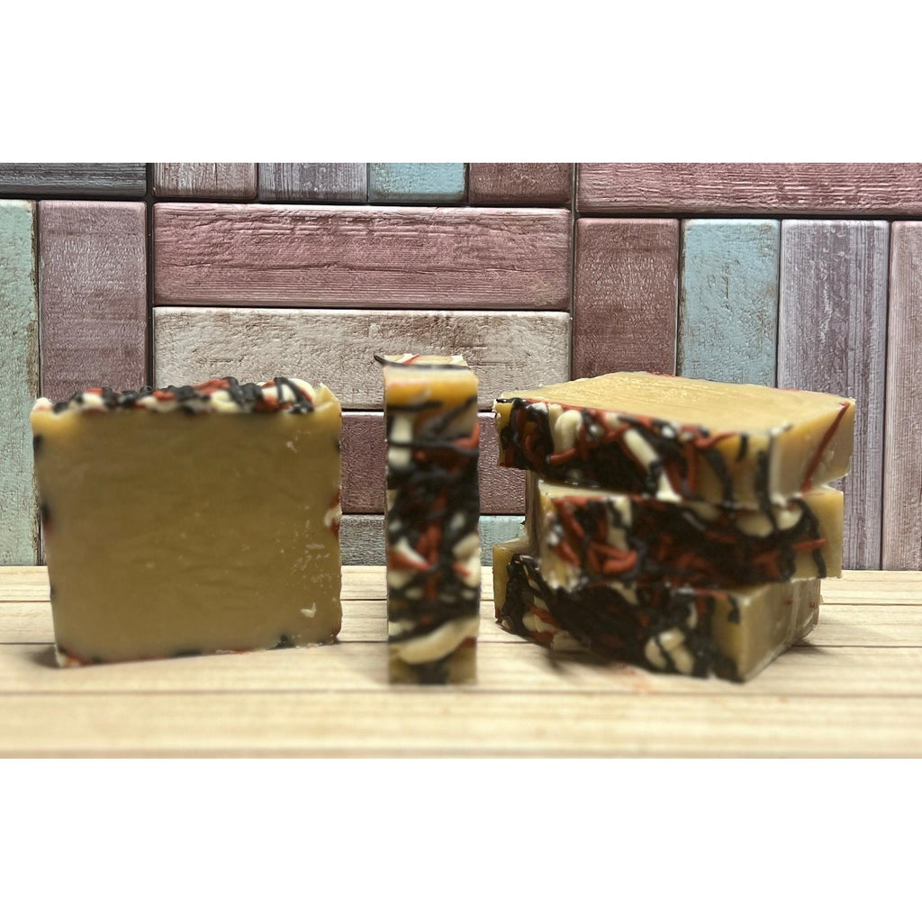 Three bars of Apple Cider soap with a marbled pattern on a wooden surface, with a wooden paneled background.