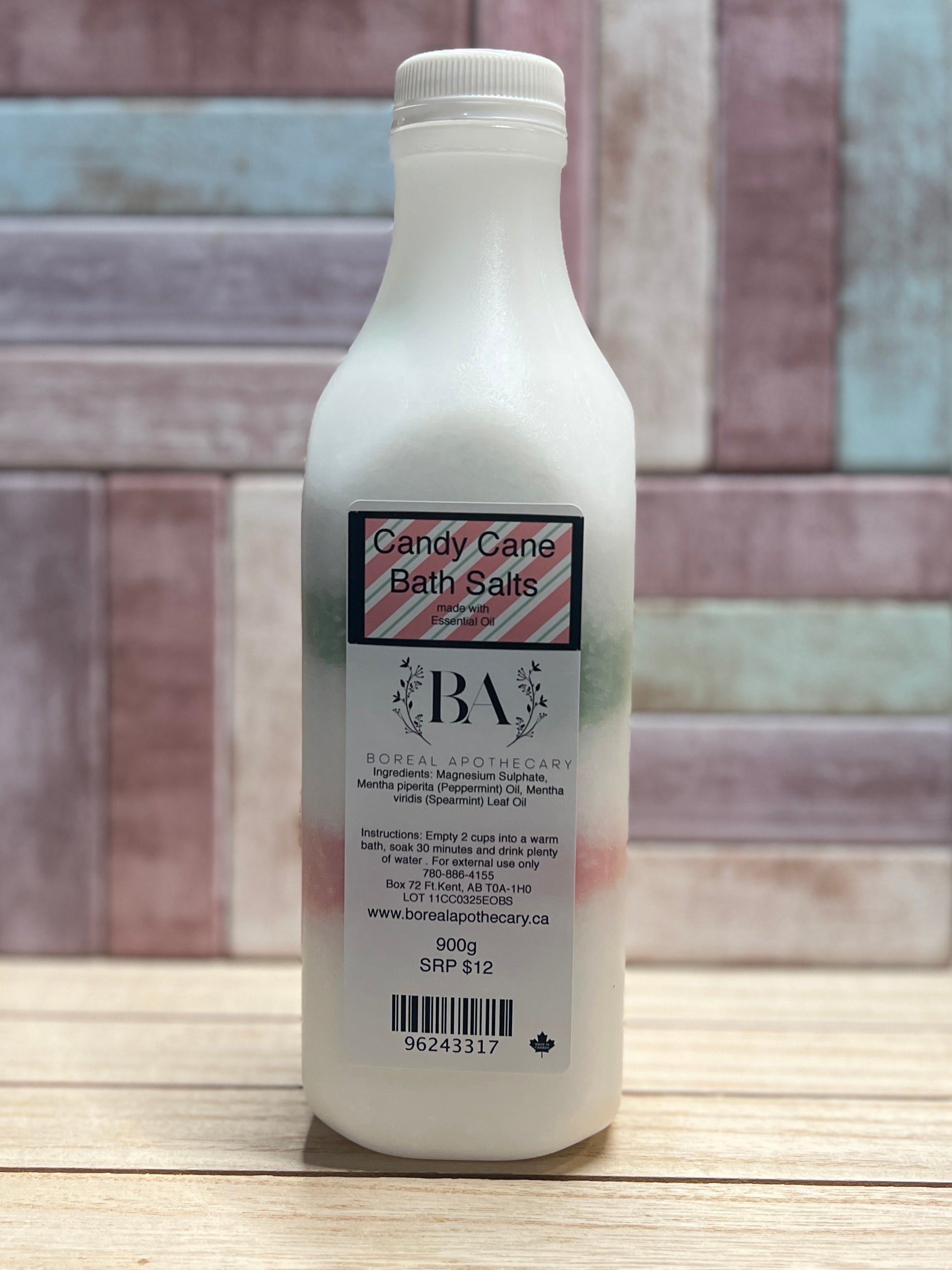 Bottle of Candy Cane Bath Salts with a label on a wooden surface and tiled wall background