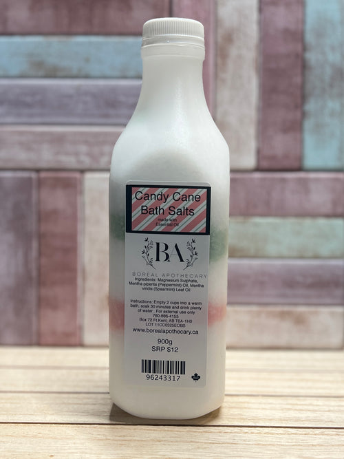 Bottle of Candy Cane Bath Salts with a label on a wooden surface and tiled wall background