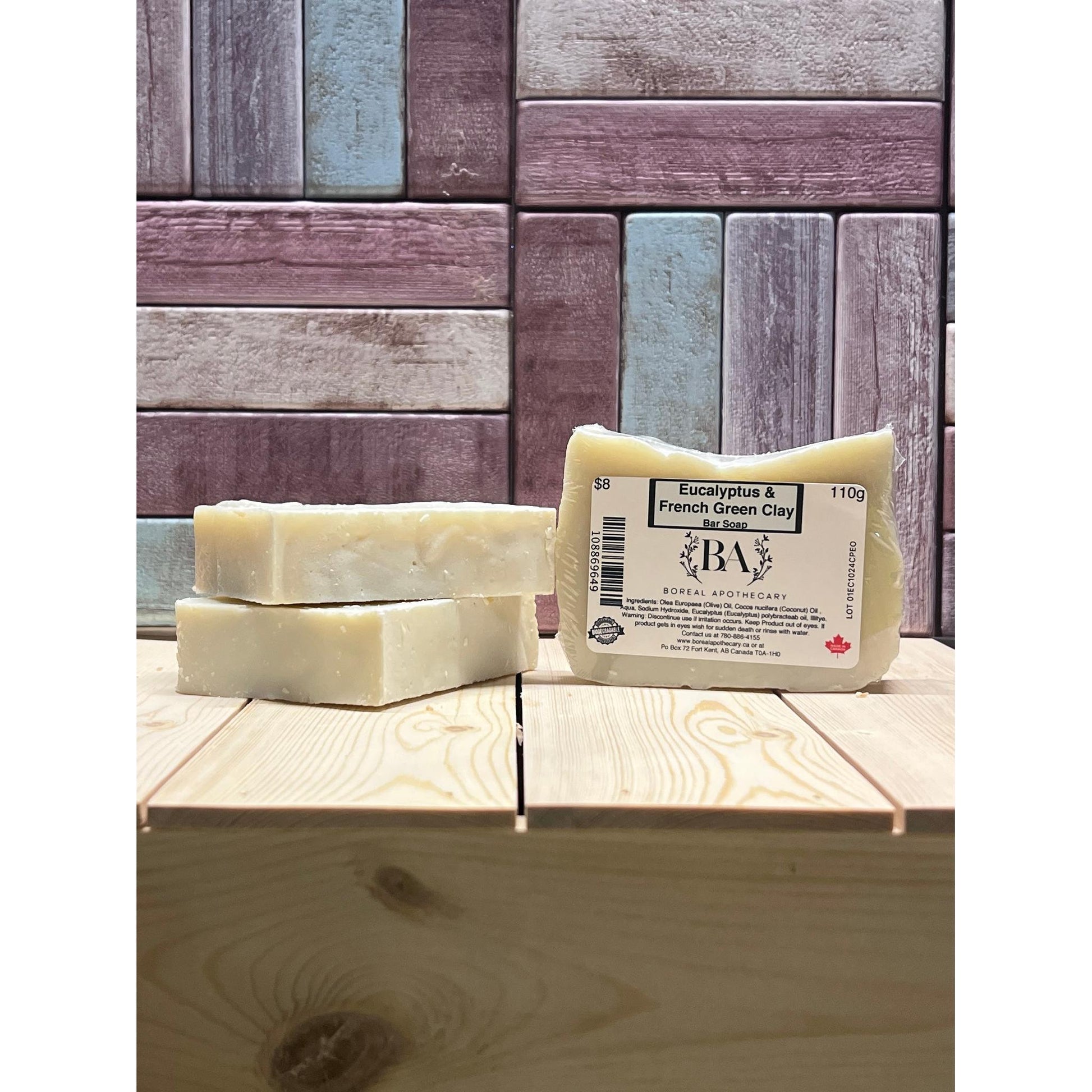 Three bars of soap with a visible brand label on a wooden surface against a wooden panel background.