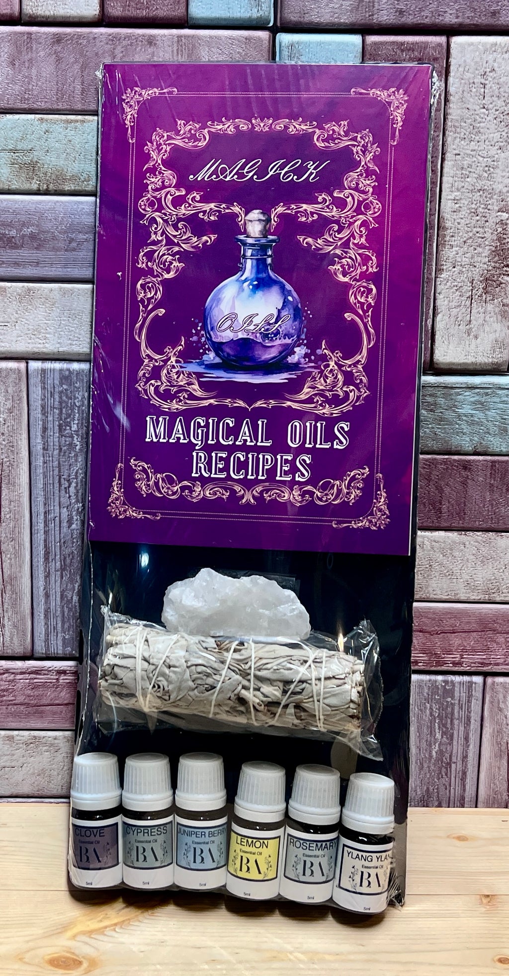 Set of bottles labeled 'BA' with a purple book titled 'Magical Oils Recipes' on a wooden surface.