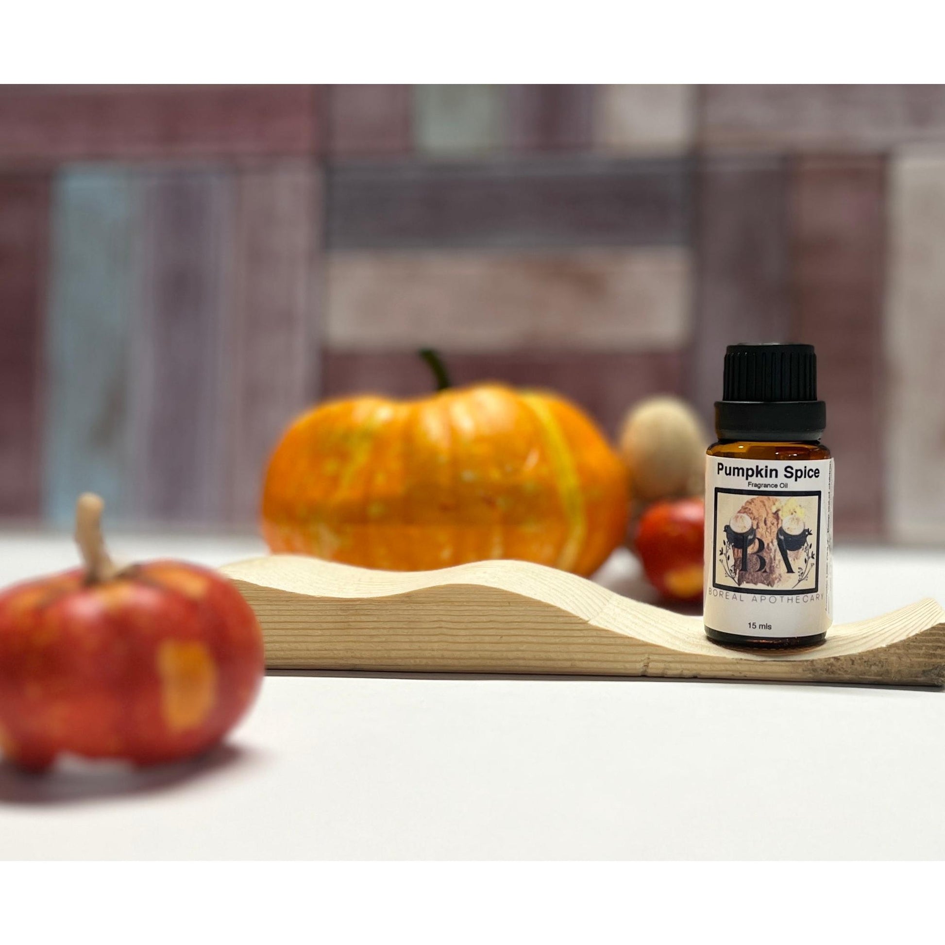 Bottle of 'Pumpkin Spice Fragrance Oil with pumpkins on a wooden board.