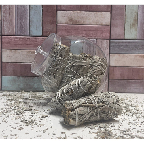 Two bundles of sage wrapped in twine on a textured surface with a wooden panel background.