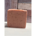 Square bar of soap with specks on a wooden surface