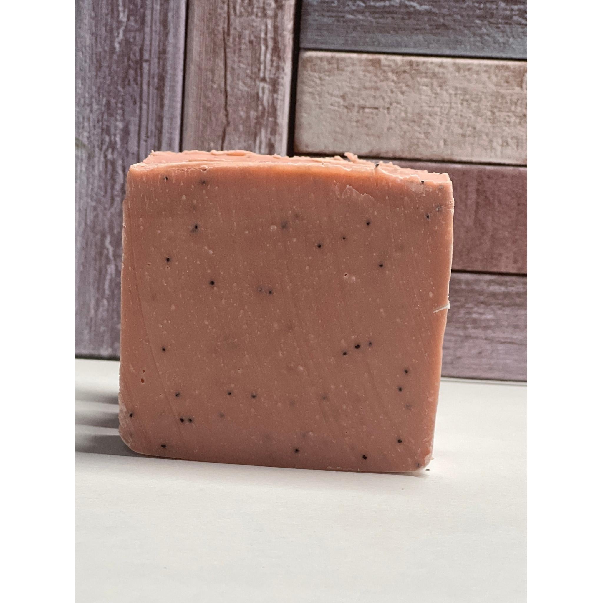 Square bar of soap with specks on a wooden surface