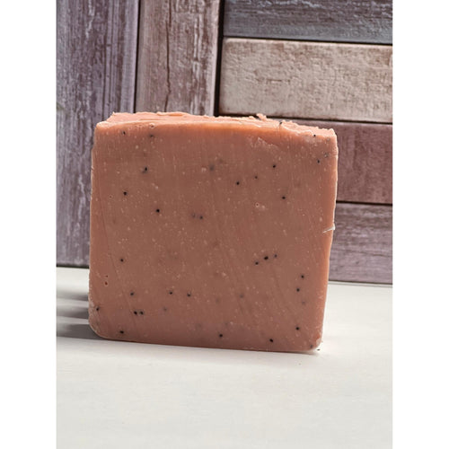Square bar of soap with specks on a wooden surface