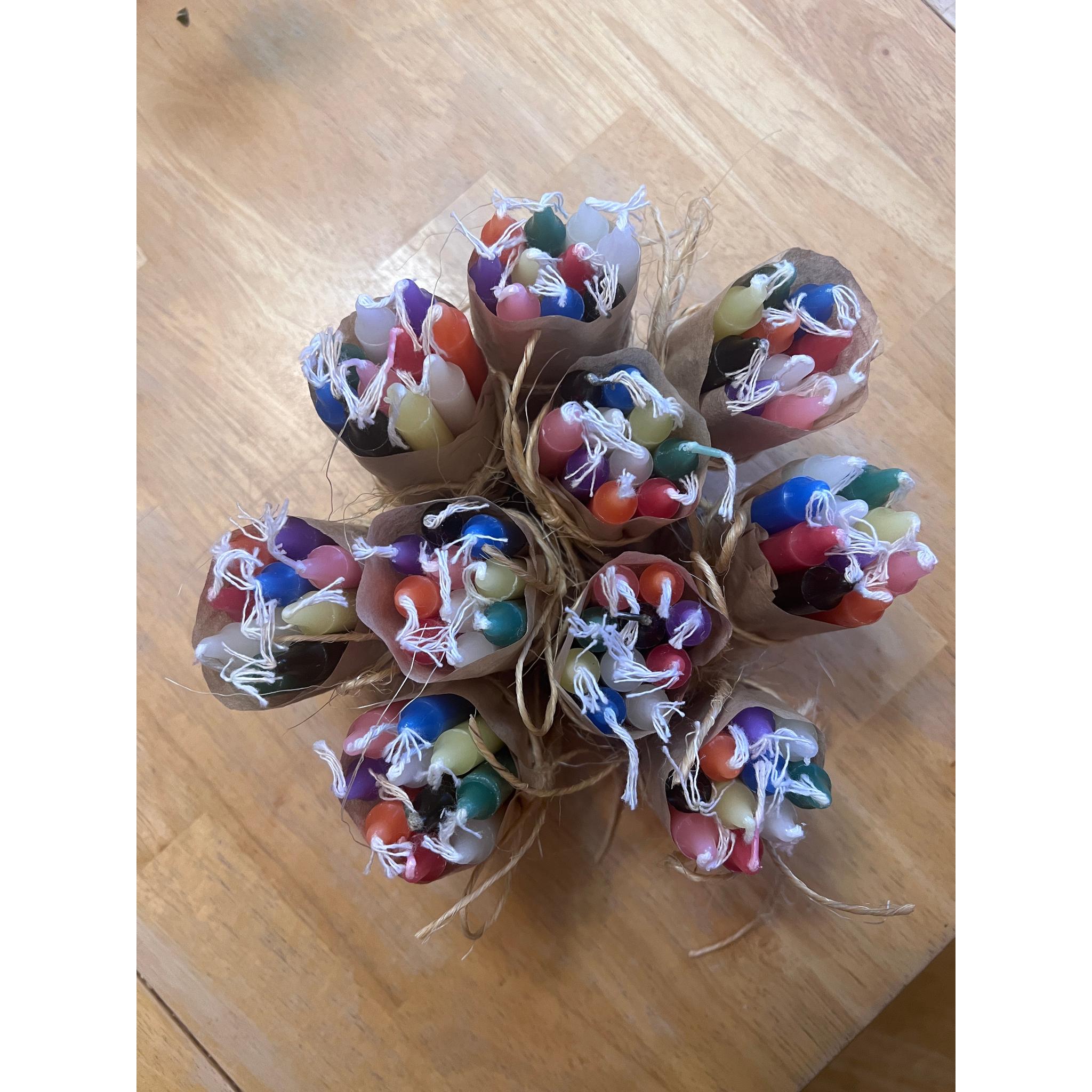 Colourful candles in paper wraps tied with twine on a wooden surface with a background.