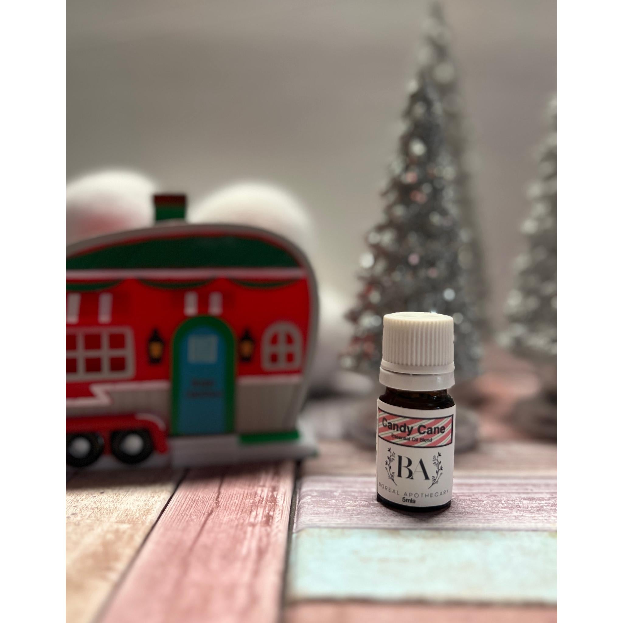 Small bottle labeled 'candy cane' on a wooden surface with Christmas decorations in the background.