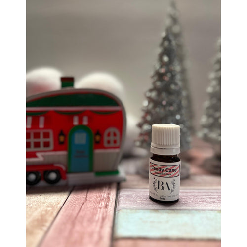 Small bottle labeled 'candy cane' on a wooden surface with Christmas decorations in the background.