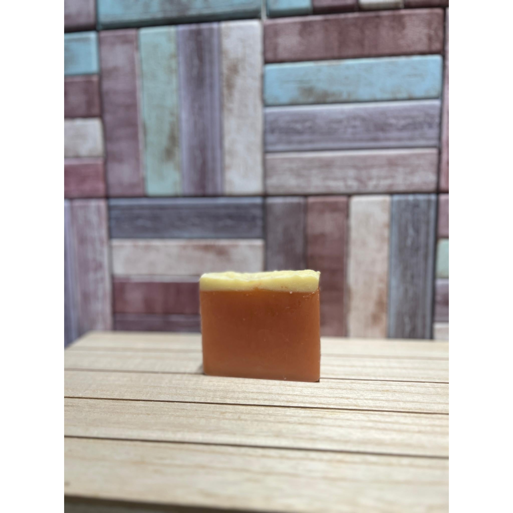 Bar of soap on a wooden surface with a multicolored tile background