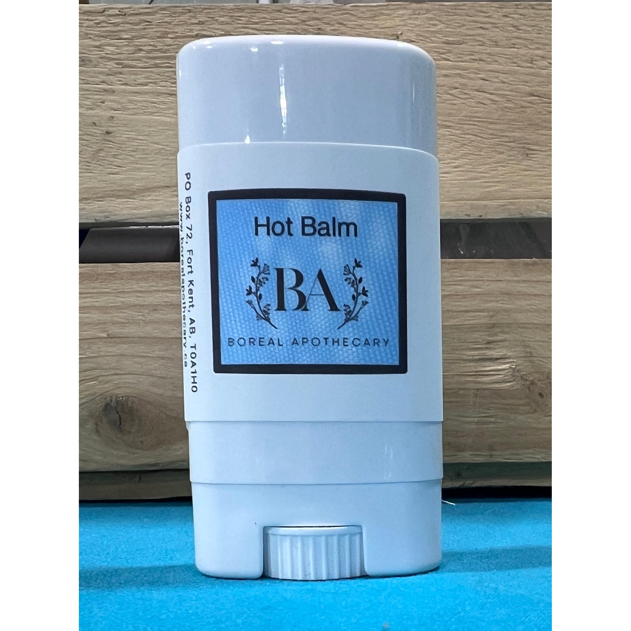 Boreal Apothecary Hot Balm stick on a blue surface with wooden background