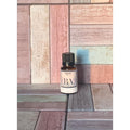 Small bottle labeled 'Agave BA' on a wooden surface with a multicolored background