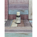 Bottle labeled Clarify Essential oil blend on a wooden surface with a multicolored background