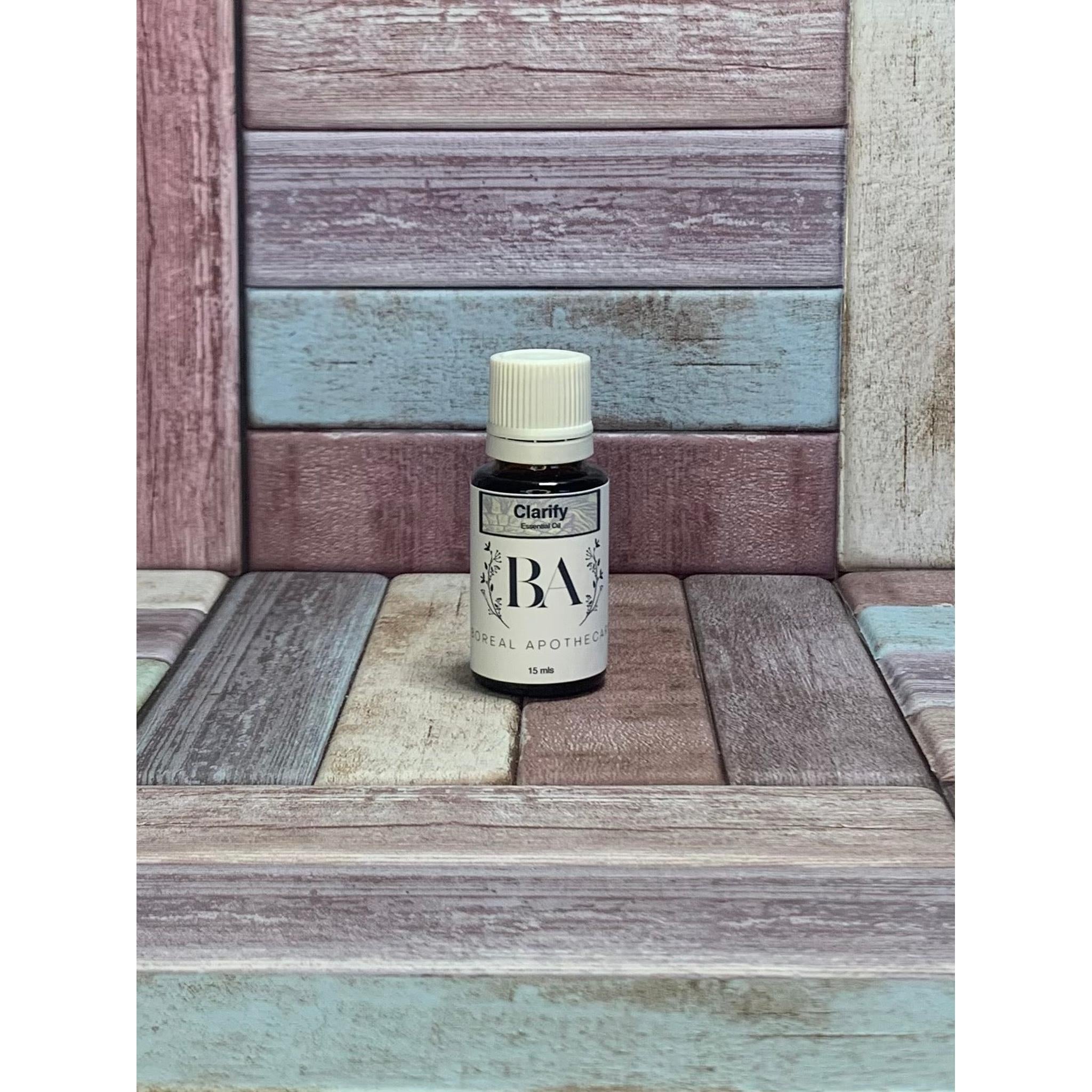 Bottle labeled Clarify Essential oil blend on a wooden surface with a multicolored background