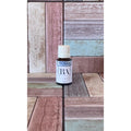 Bottle labeled 'Sore Muscle' on a wooden surface with a multicolored background