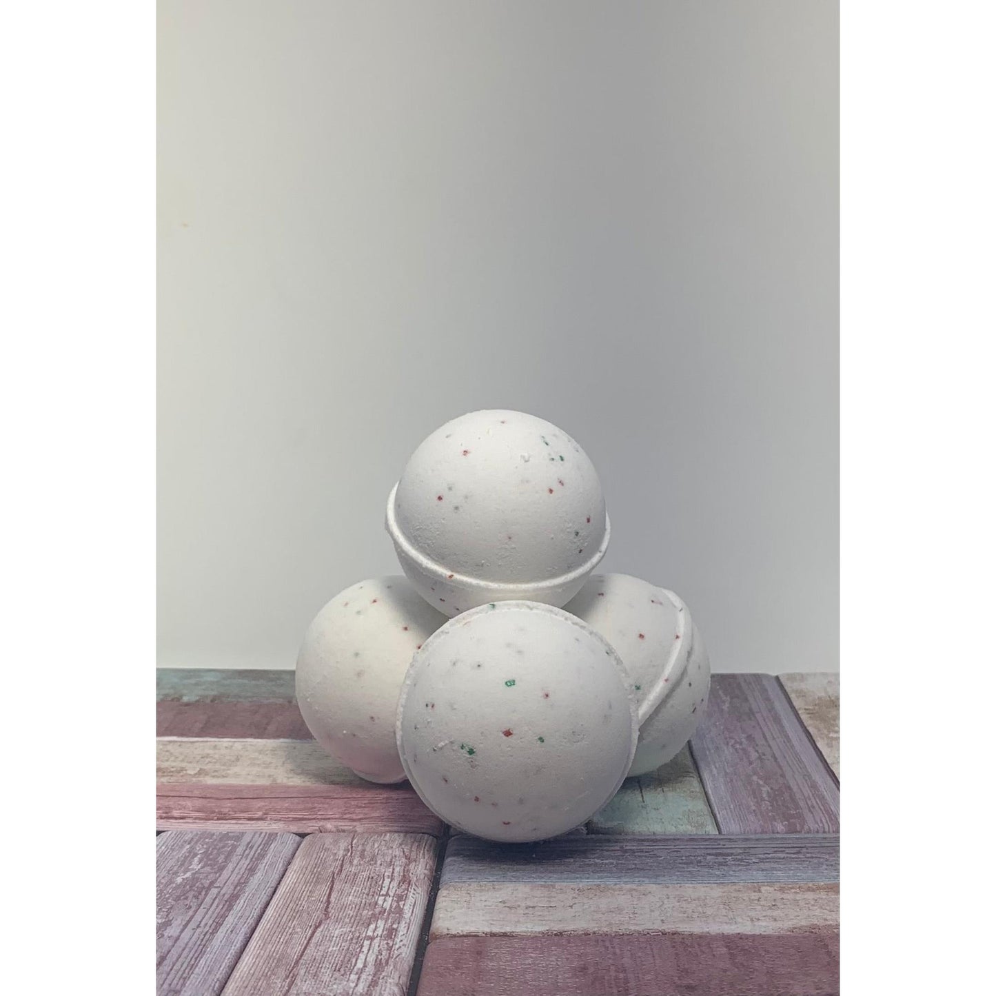 Three speckled bath bombs on a wooden surface with a plain background