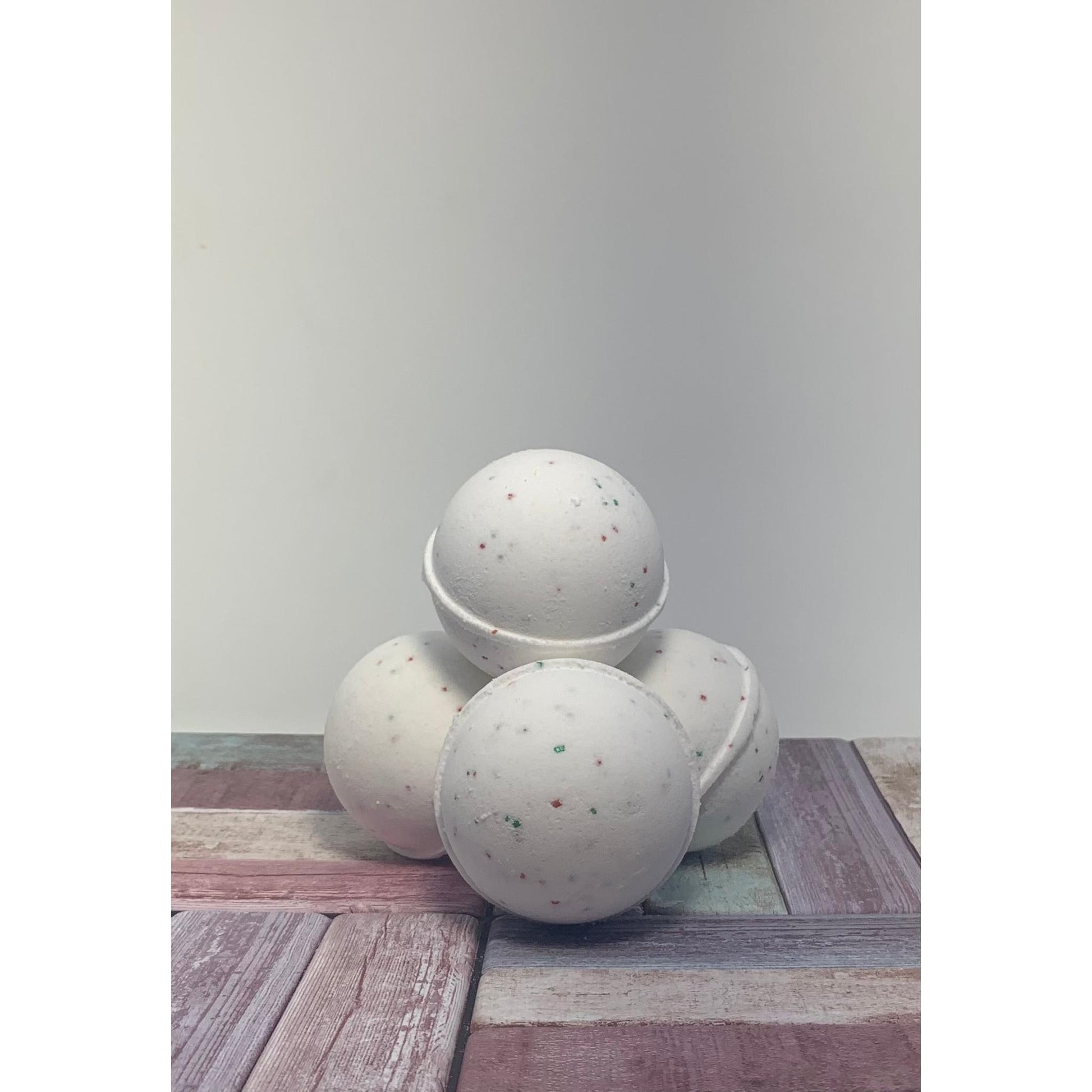 Three speckled bath bombs on a wooden surface with a plain background