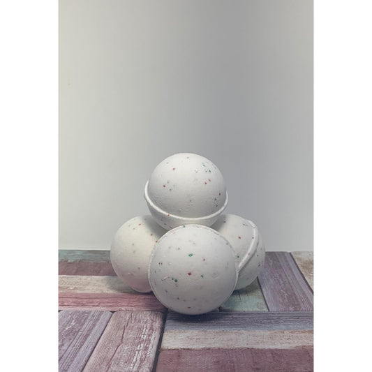 Three speckled bath bombs on a wooden surface with a plain background