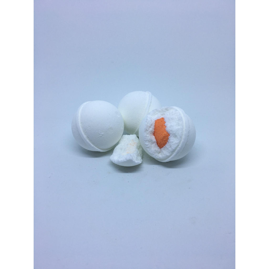 Three white bath bombs with an orange center on a light blue background