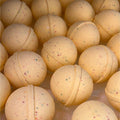 Close-up of yellow bath bombs with specks on a clear background