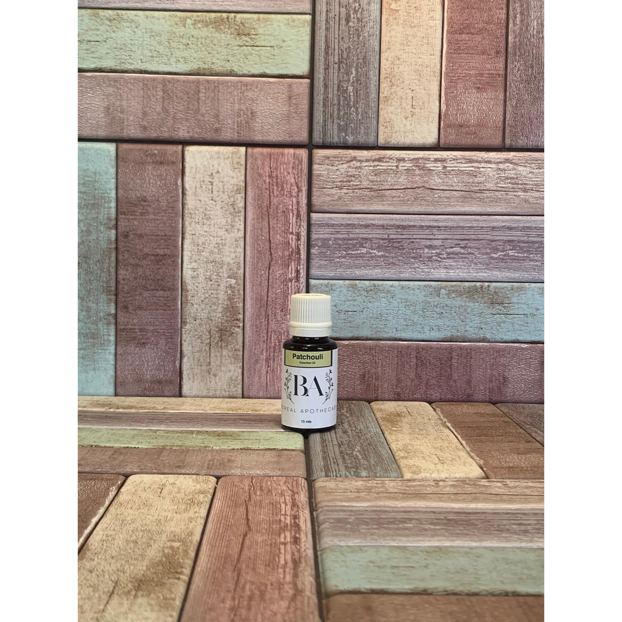 Bottle of patchouli essential oil  on a wooden surface with a multi-coloured pattern