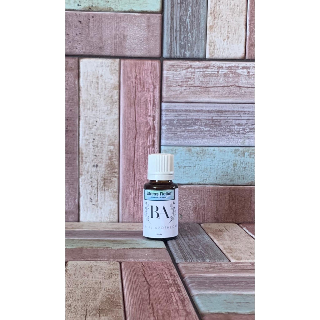 Small bottle labeled stress relief essential oil by 'BA' on a wooden panel background